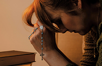Woman praying with rosary beads